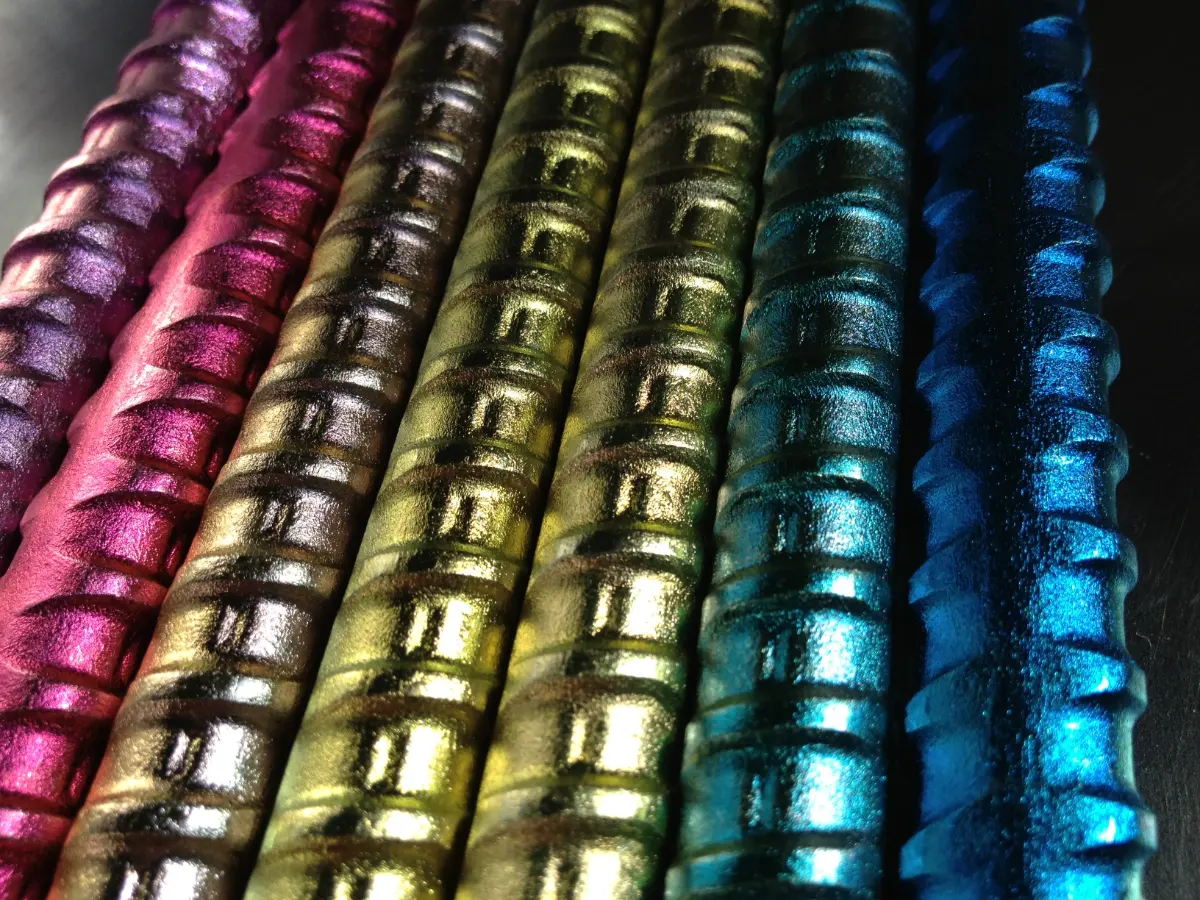 Close-up of ribbed metal rods with iridescent pink, gold, green and blue surfaces